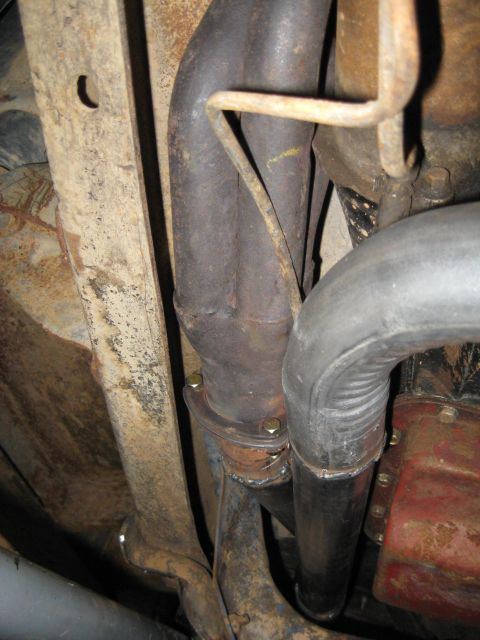 1978 Ford Bronco - Close-up view of the exhaust system components beneath a vehicle, revealing signs of age and use.