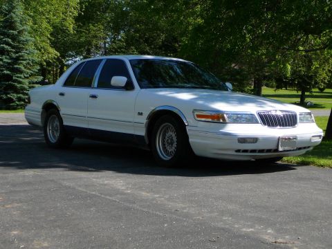 1997 Mercury Grand Marquis - A white 1997 Mercury Grand Marquis is parked on a driveway with trees in the background.