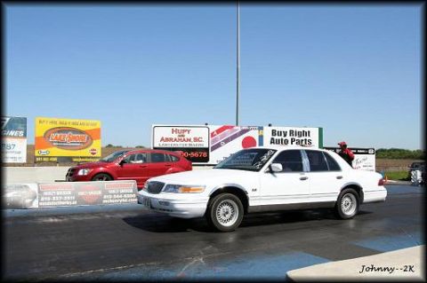 1997 Mercury Grand Marquis - White 1997 Mercury Grand Marquis at a drag strip, with a red car and billboards in the background.