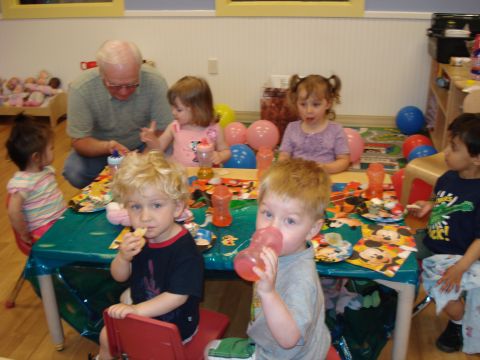 2000 Ford Crown Victoria - A group of children and an adult are seated around a table, enjoying a party with balloons and themed decorations.