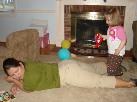 2000 Ford Crown Victoria - A child plays with a toy airplane while a woman lies on the floor in a living room.