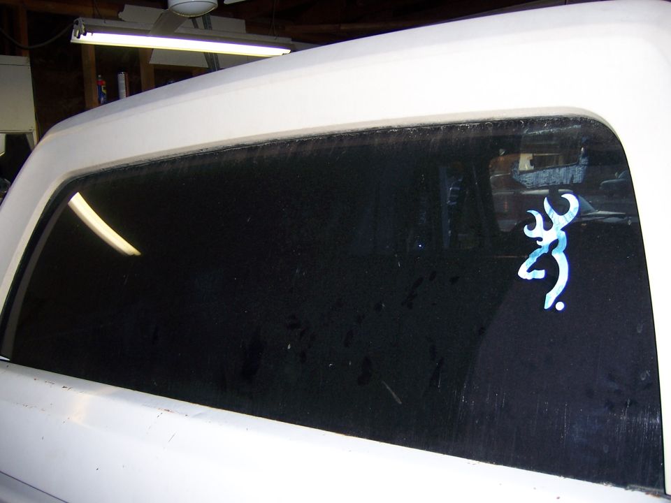 White vehicle's rear side window with a blue Browning deer logo sticker