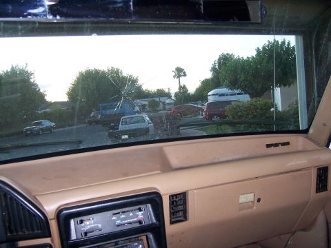 1991 Ford Bronco - View from inside a vehicle's cabin, looking out through the windshield at a street with parked vehicles.