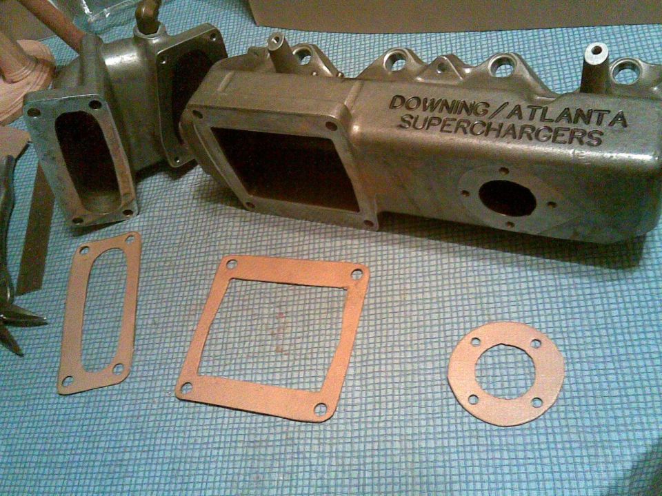 Downing/Atlanta Supercharger intake manifold casting with three paper gaskets on a blue mat