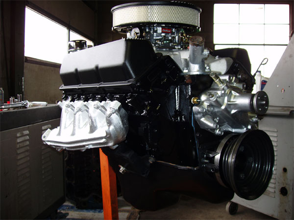 Black V8 engine with chrome air cleaner and intake manifold, on an orange stand