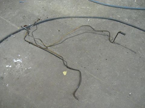 1978 Ford Bronco - These metal brake lines are coiled and bent on the ground, possibly removed from a vehicle.