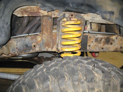 1978 Ford Bronco - Close-up view of a yellow coil spring and a large off-road tire, showing suspension components.