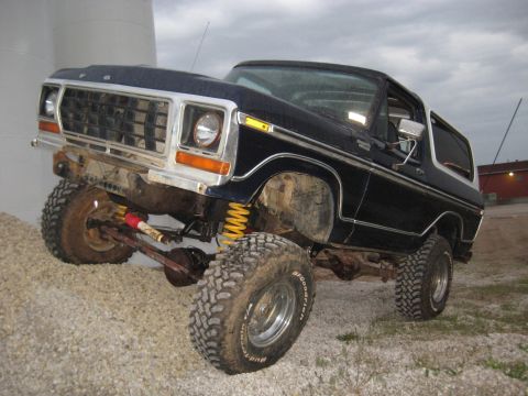 1978 Ford Bronco - This lifted 1978 Ford Bronco is parked on a gravel surface with a cloudy sky overhead.
