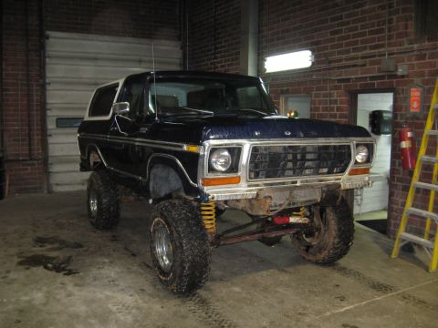 1978 Ford Bronco - This 1978 Ford Bronco features a significant lift kit and off-road tires, parked indoors.