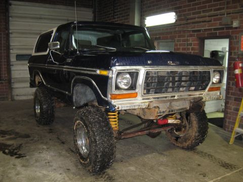 1978 Ford Bronco - This lifted Ford Bronco is parked inside a garage with a roll-up door in the background.