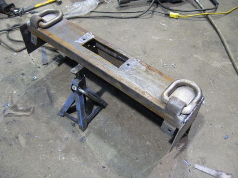 1978 Ford Bronco - A metal bumper with tow hooks is supported by jack stands in a workshop environment.