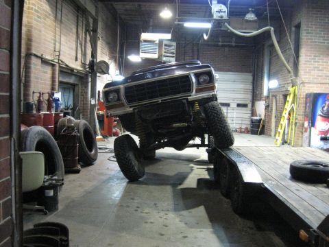 1978 Ford Bronco - A lifted Ford Bronco is being loaded onto a trailer inside a workshop.