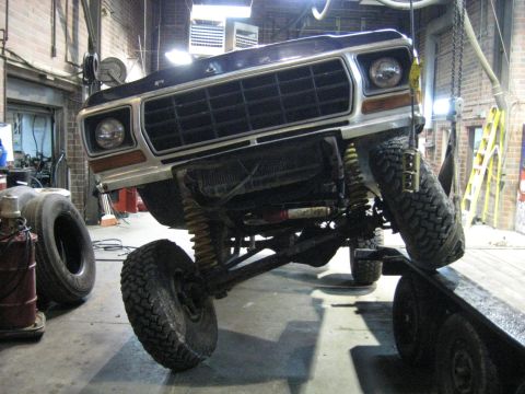 1978 Ford Bronco - A lifted Ford F-Series truck is being worked on in a garage, with its front end elevated.