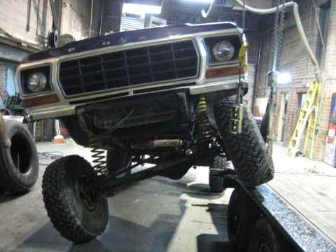 1978 Ford Bronco - The front grille and suspension of a 1978 Ford Bronco are visible as the vehicle is lifted.