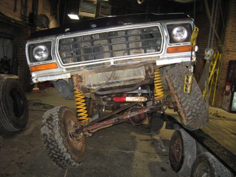 1978 Ford Bronco - The front of a lifted Ford truck is shown with its suspension components exposed, suggesting it is undergoing repairs or modifications.