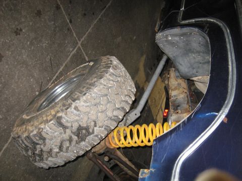 1978 Ford Bronco - Spare tire and suspension components are visible next to a blue vehicle's fender.