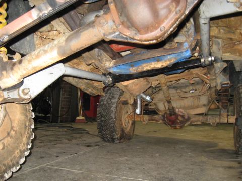 1978 Ford Bronco - The undercarriage of a vehicle, modified suspension and large tires, is shown in this photograph.