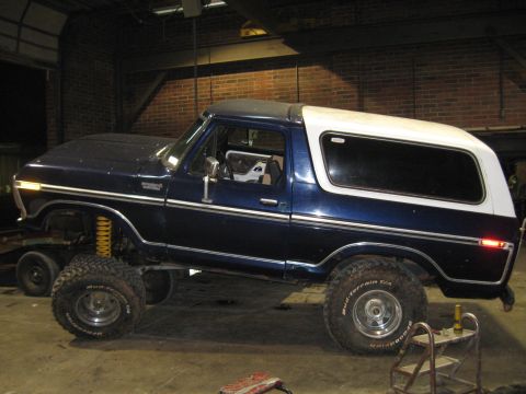 1978 Ford Bronco - A lifted 1978 Ford Bronco with a two-tone blue and white exterior sits in a garage.