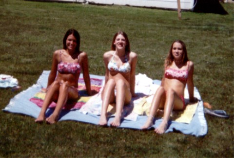 1990 Ford Taurus - Three women relax on a blanket outdoors on a sunny day.
