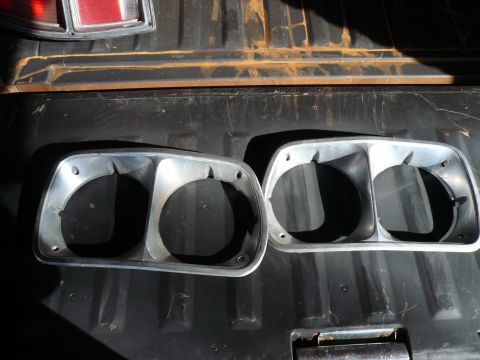 1975 Ford Ranchero - Two headlight bezels are shown in the bed of a pickup truck, with a taillight visible at the top.