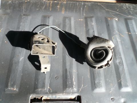1975 Ford Ranchero - Two car horns, likely from a vehicle, are shown on a dark, possibly truck bed, surface.