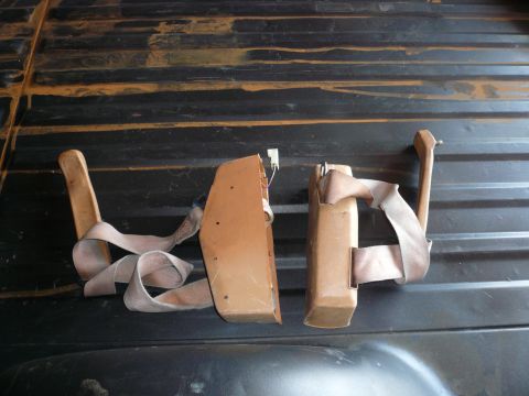1975 Ford Ranchero - Two seatbelt retractors are shown lying on a dark, ribbed surface, possibly a truck bed.