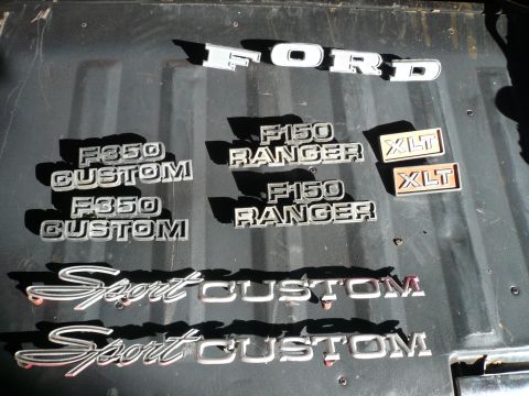1975 Ford Ranchero - Collection of Ford emblems including F350 Custom, F150 Ranger, XLT, and Sport Custom trim pieces.