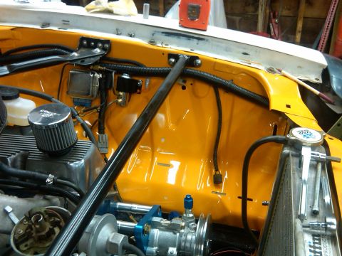 1978 Ford Mustang II - Engine bay of an orange truck under build showing radiator, wiring loom, brake master cylinder, and distributor.