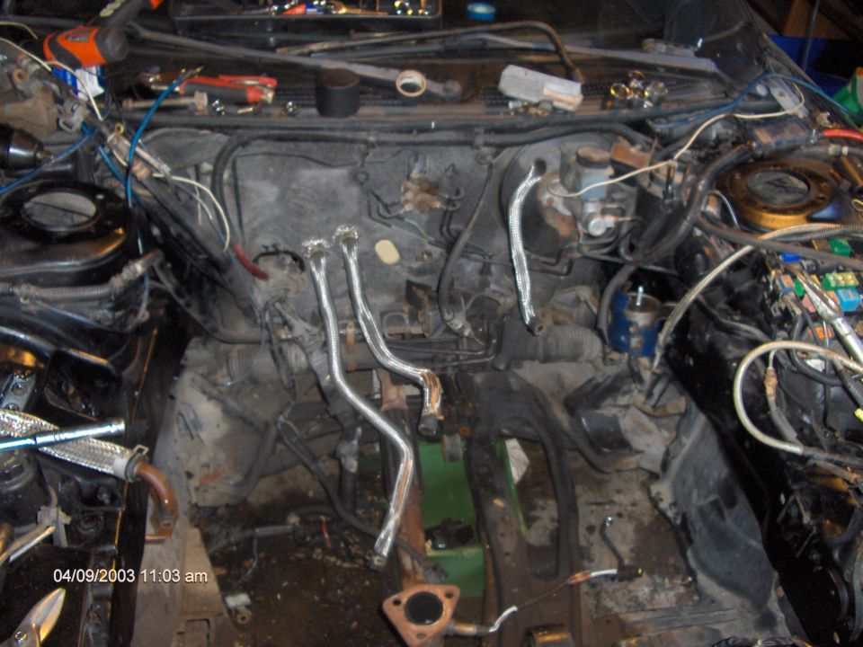 Empty engine bay of a car under repair with hoses and wiring exposed