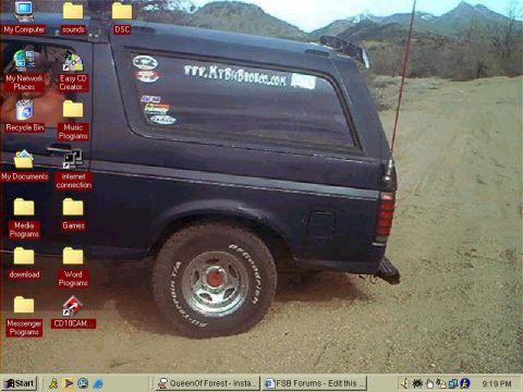 1987 Ford Bronco - A Windows desktop wallpaper screenshot, complete with icons and taskbar, showing a dark blue two-door Ford Bronco from the rear three-quart…