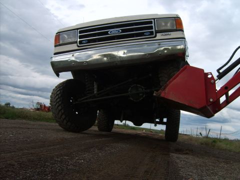 1989 Ford Bronco - Front end of a Ford truck, possibly an F-Series, equipped with a loader attachment.