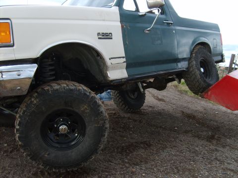 1989 Ford Bronco - A modified Ford F-250 with a two-tone paint job and lifted suspension is shown from the side.
