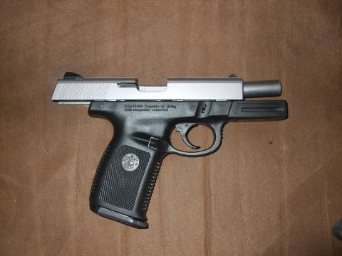 1988 Ford Bronco - A pistol with a silver slide and black grip is shown against a brown background.