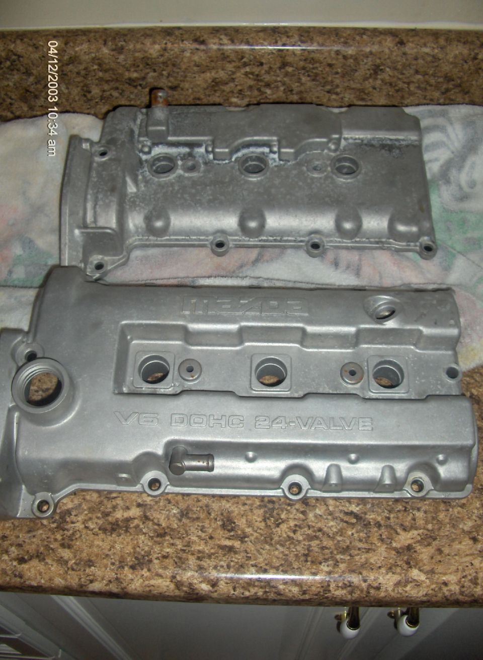 Two silver engine valve covers, one labeled MAZDA and V6 DOHC 24-VALVE