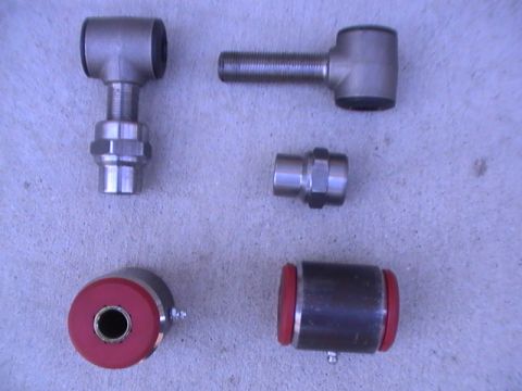 1997 Ford Ranger - Various metal suspension parts with rubber bushings are laid out on a concrete surface.