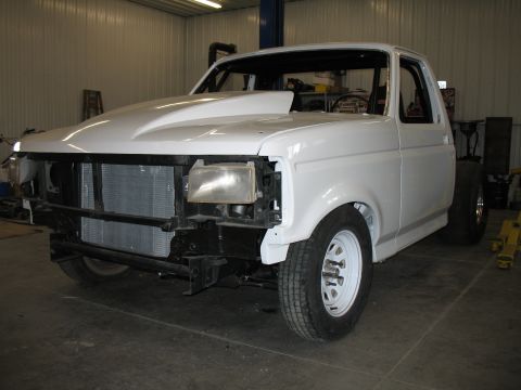 1994 Ford F-150 - This white pickup truck is in a garage, appearing to be undergoing some modifications or repairs.
