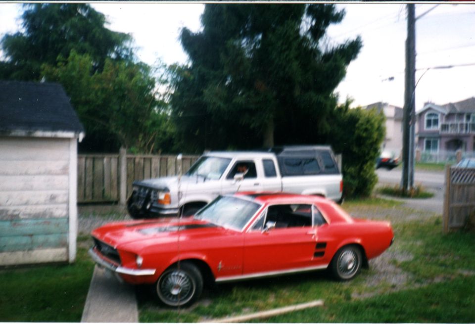 red 1967 Mustang coupe parked in front of a silver pickup truck