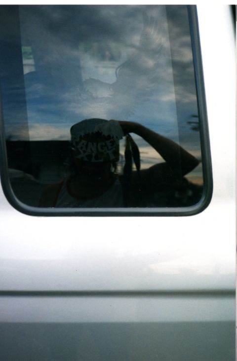 1989 Ford Bronco - Reflection of a person wearing a hat and tank top is visible in the side window of a silver vehicle.