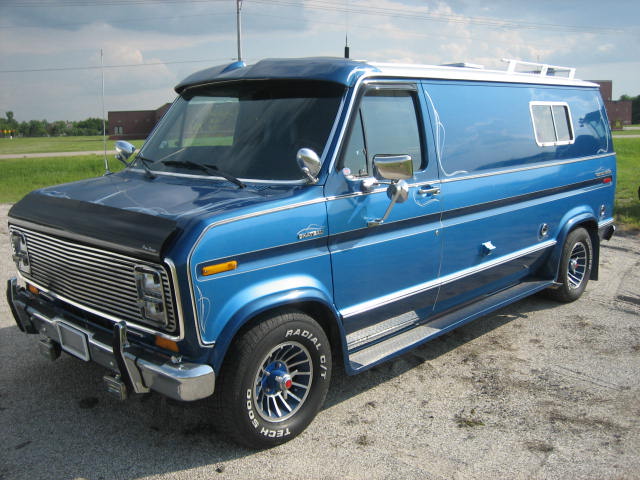 Blue van with chrome grille, side steps, and custom pinstriping. Visible front quarter panel and side