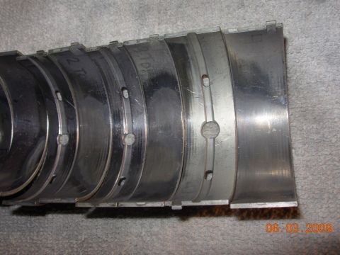 1995 Ford Taurus - Engine bearings shown in a row, some with part numbers visible, on a textured surface.