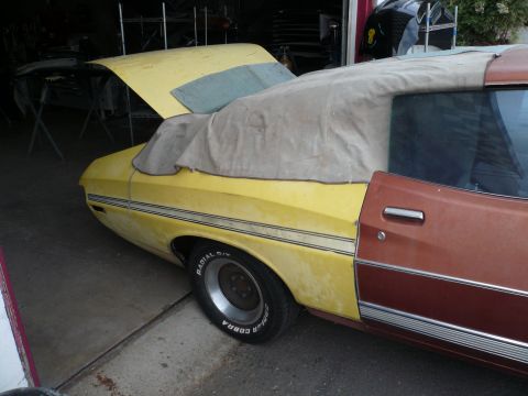 1975 Ford Ranchero - A two-tone Ford Ranchero with its hood up and a cover over the convertible top sits in a garage.