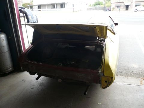 1975 Ford Ranchero - The rear of a yellow 1975 Ford Ranchero is shown with its trunk open, revealing the cargo area.