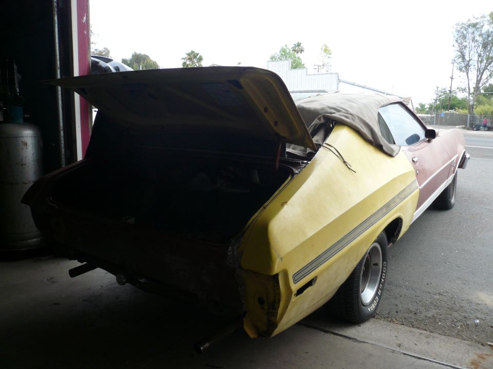 1975 Ford Ranchero with trunk open, showing interior. Yellow and red paint