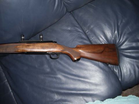1991 Ford Bronco - A rifle with a wooden stock is shown resting on a dark blue leather surface.