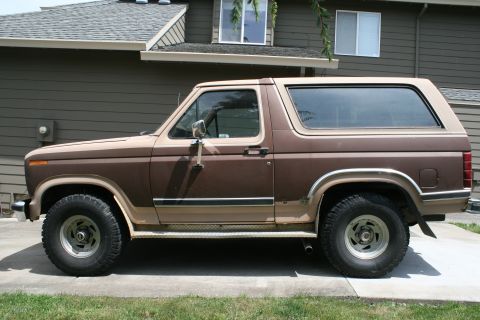 1984 Ford Bronco - Side profile of a brown 1984 Ford Bronco with a tan top.