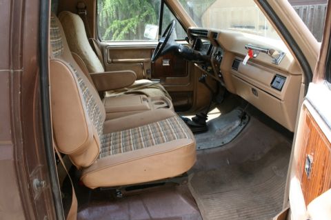 1984 Ford Bronco - Interior of a brown truck, likely from the early 1980s, with plaid seat inserts and wood-grain trim.