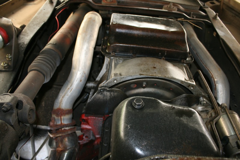 Underside view of engine oil pan and exhaust pipes with rust