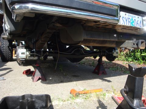 1989 Ford Bronco - The rear suspension and axle of a 1989 Ford Bronco are visible, supported by jack stands.