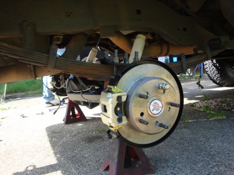 1989 Ford Bronco - Close-up view of a vehicle's rear axle and suspension system, supported by jack stands.