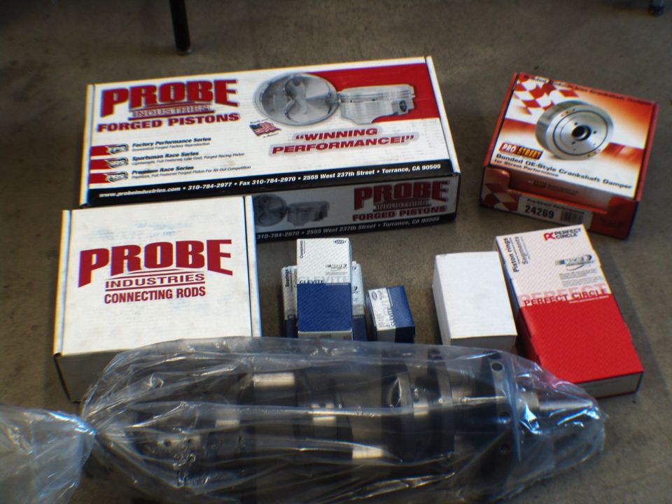 Boxes of Probe Industries forged pistons and connecting rods, plus a crankshaft damper and a crankshaft